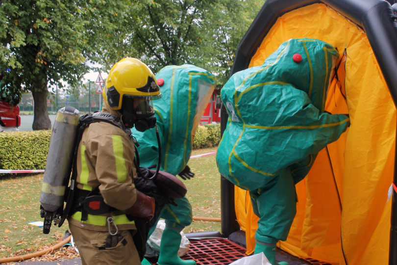 Firefighters wearing “hazmat” suits designed to protect them from toxic gases enter a decontamination tent as part of the exercise