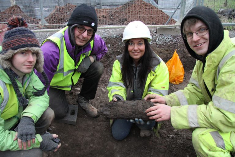 Archaelogists with the wooden post which was extracted in February