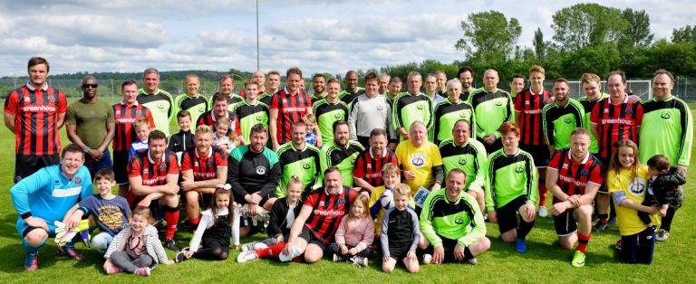 The two teams and younger family members lined up together at the end of the charity match