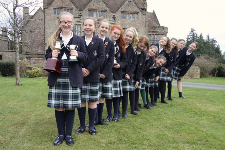 Hattie Candler (front) with her individual trophies from the Oswestry Youth Music Festival and fellow performers from Adcote School who also won a trophy for best vocal ensemble