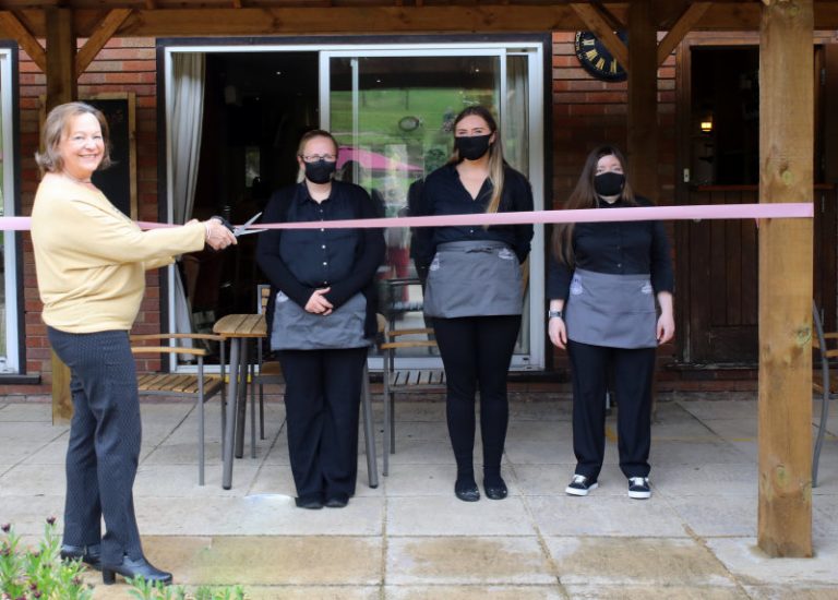 Bobby Darley cutting the opening ribbon, with the Covid regulation Waitresses Katie, Ruth & Lisa ready to serve members & visitors