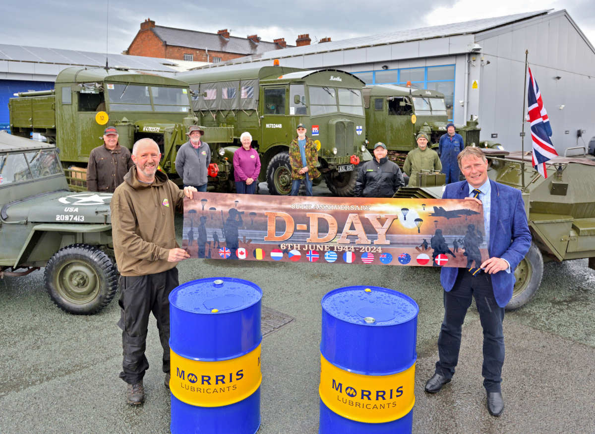 Morris Lubricants’ chairman Andrew Goddard (right) presents drums of oil to Ben Kaye on a rainy day, watched by family members and friends with their vintage military vehicles