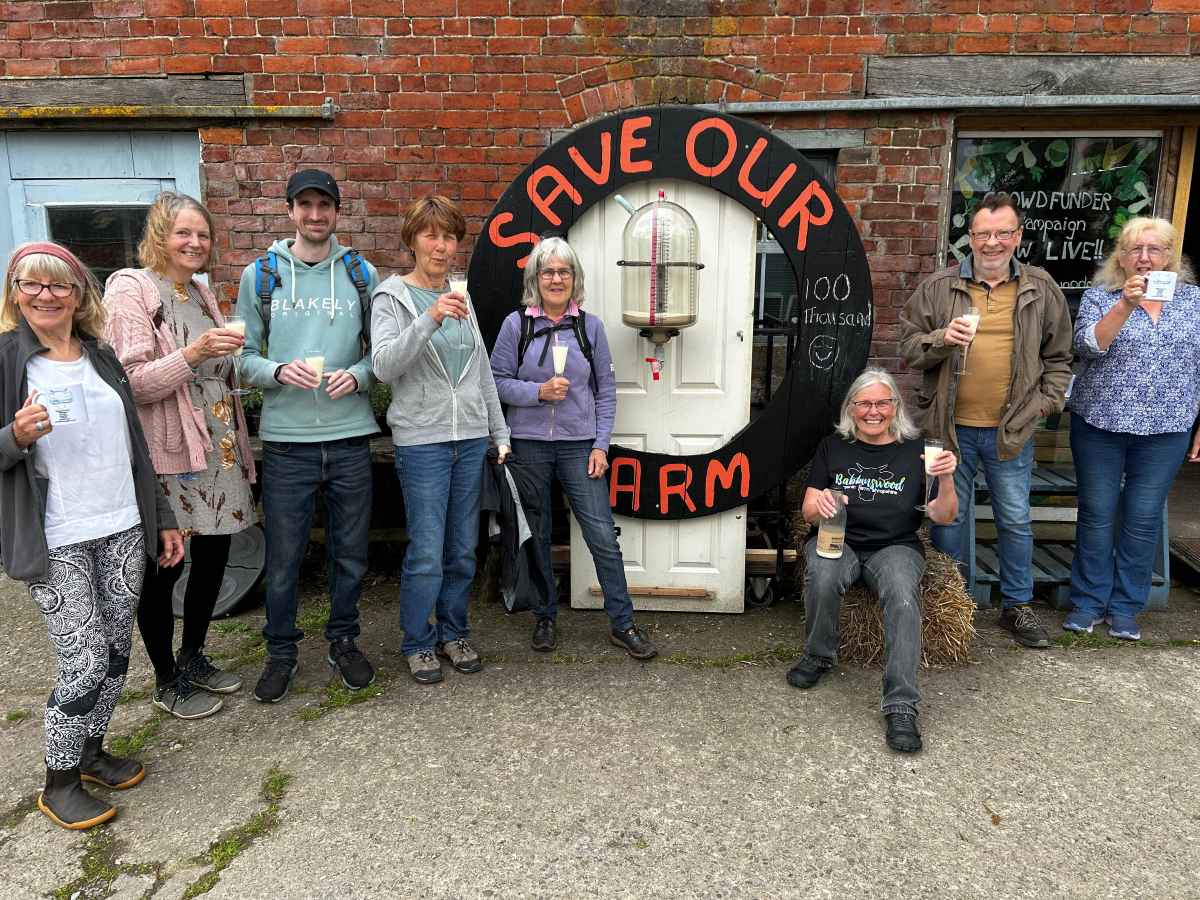 Barbara Jones of Babbinswood Farm (seated) and members of the community benefit society toast the £100,000 milestone with milk from the cow and calf dairy